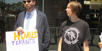 A man in a suit jacket and tie holds a sign that says "Homes 4 Tenants Not Tourists" and a woman wears a T-shirt that says "San Francisco Tenants Union" and holds a sign below the frame of the photo.