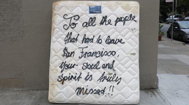 Mattress against a wall that says, "To all the people that had to leave San Francisco, your soul and spirit is truly missed!!"